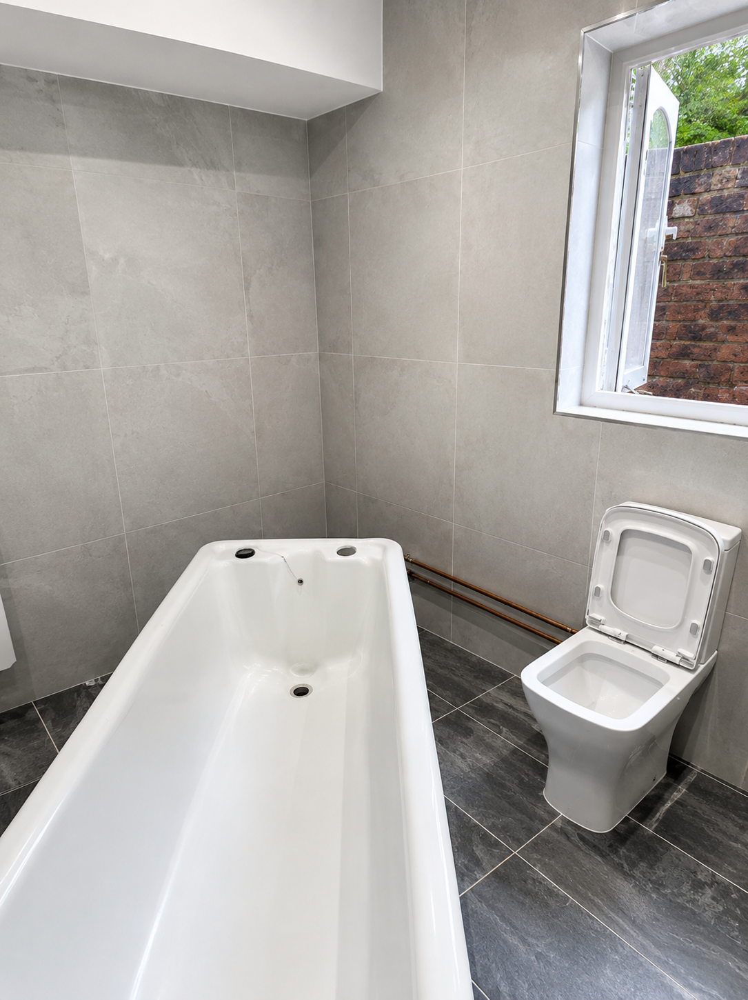 Victorian roll top bath set into position during bespoke bathroom installation in Brentwood